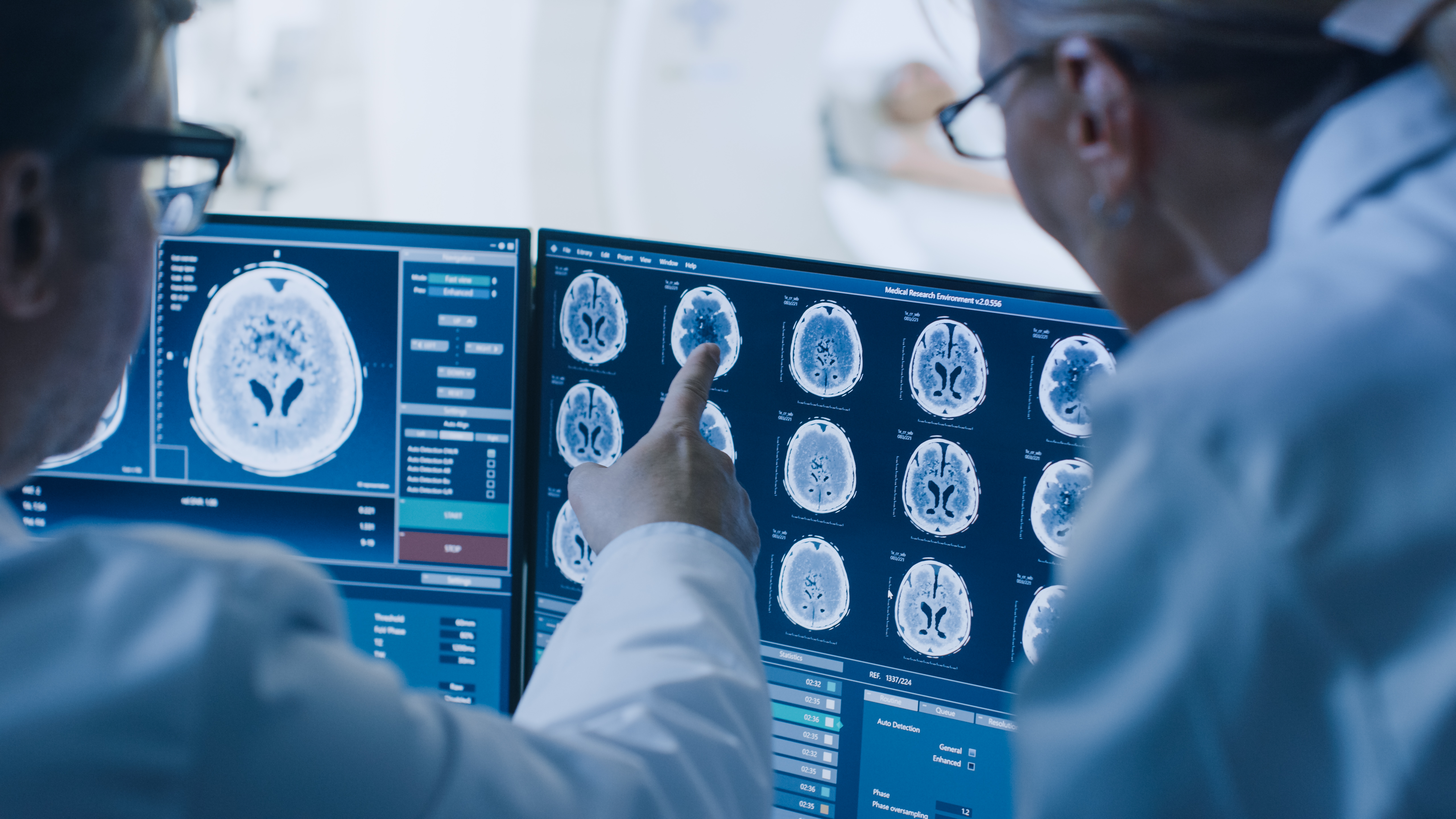 Two medical professionals in white coats looking at an imaging scan.