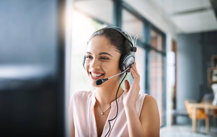 smiling woman on phone headset looking at computer smiling woman on phone headset looking at computer