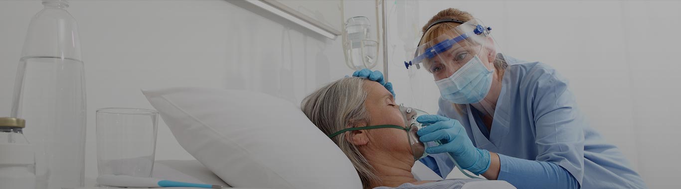 A masked respiratory therapist holds an oxygen mouth over patient's mouth