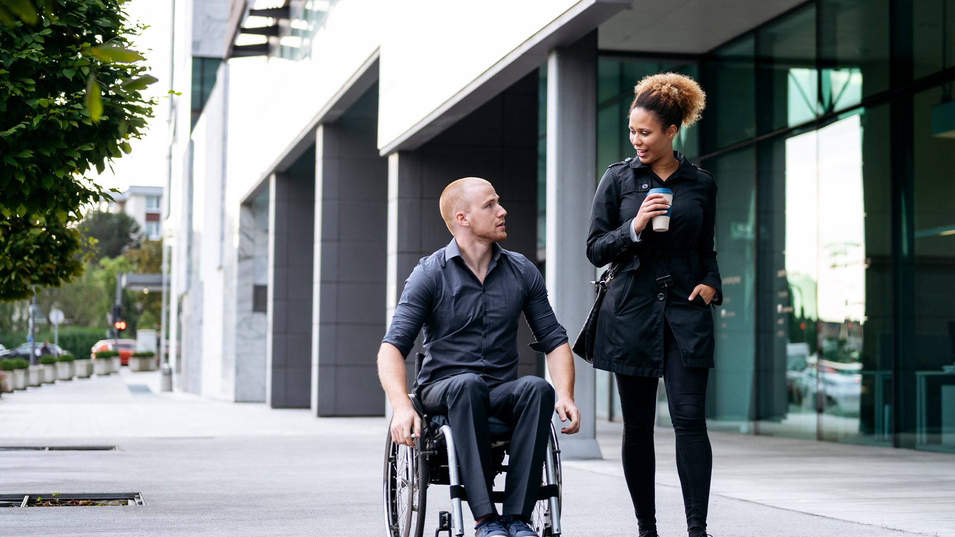Clinician walking with patient in wheelchair into the hospital