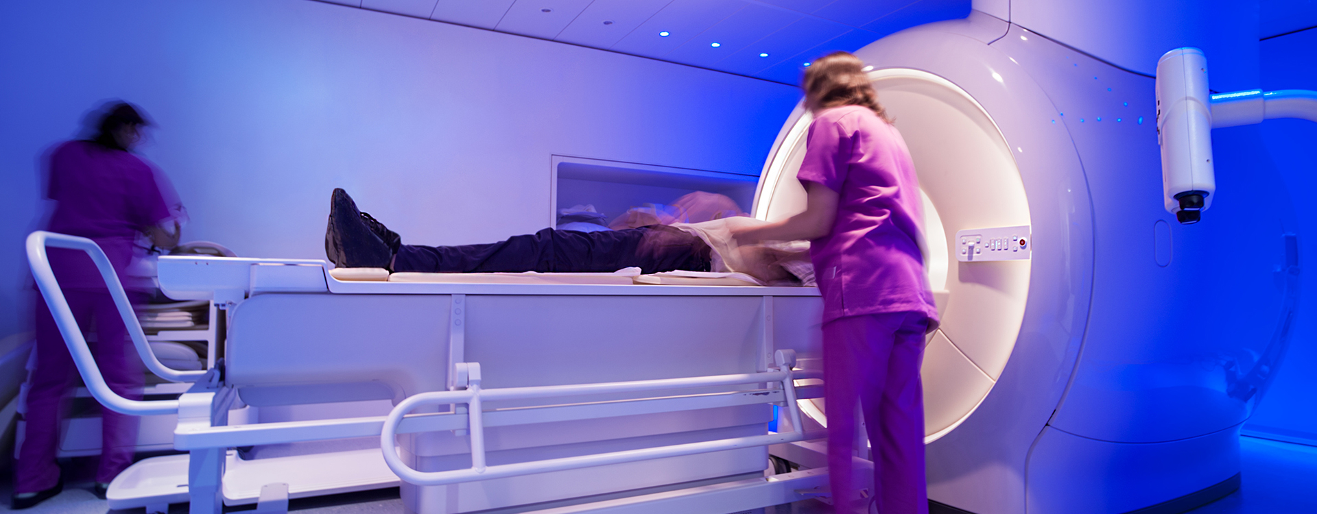 Dosimetrist placing patient's arms by their side as CAT scan begins